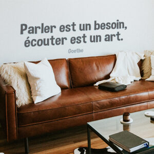 Sticker Parler est un besoin citation au dessus d'un canapé en cuir dans un salon