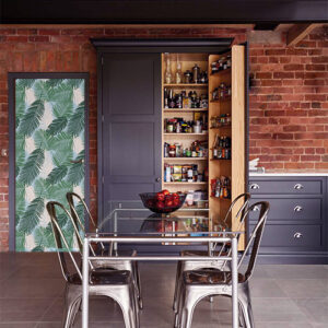 cuisine avec sticker décoratif fougères vertes collé sur la porte d'une cuisine style ancienne usine avec du mobilier en bois et métal et un mur de brique orange